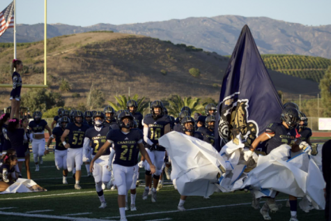 Photo Caption: The varsity football team charges through the field to take on Nordhoff High School. They came out with a 41-7 win for Dos Pueblos. Photo taken by Myles Shaddix (10)