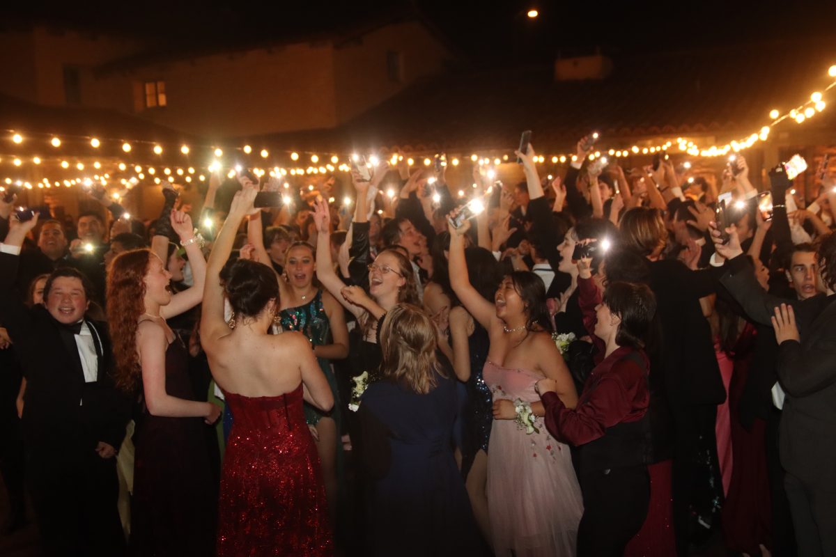 On the dance floor, attendees hold up their phone flashlights while dancing.