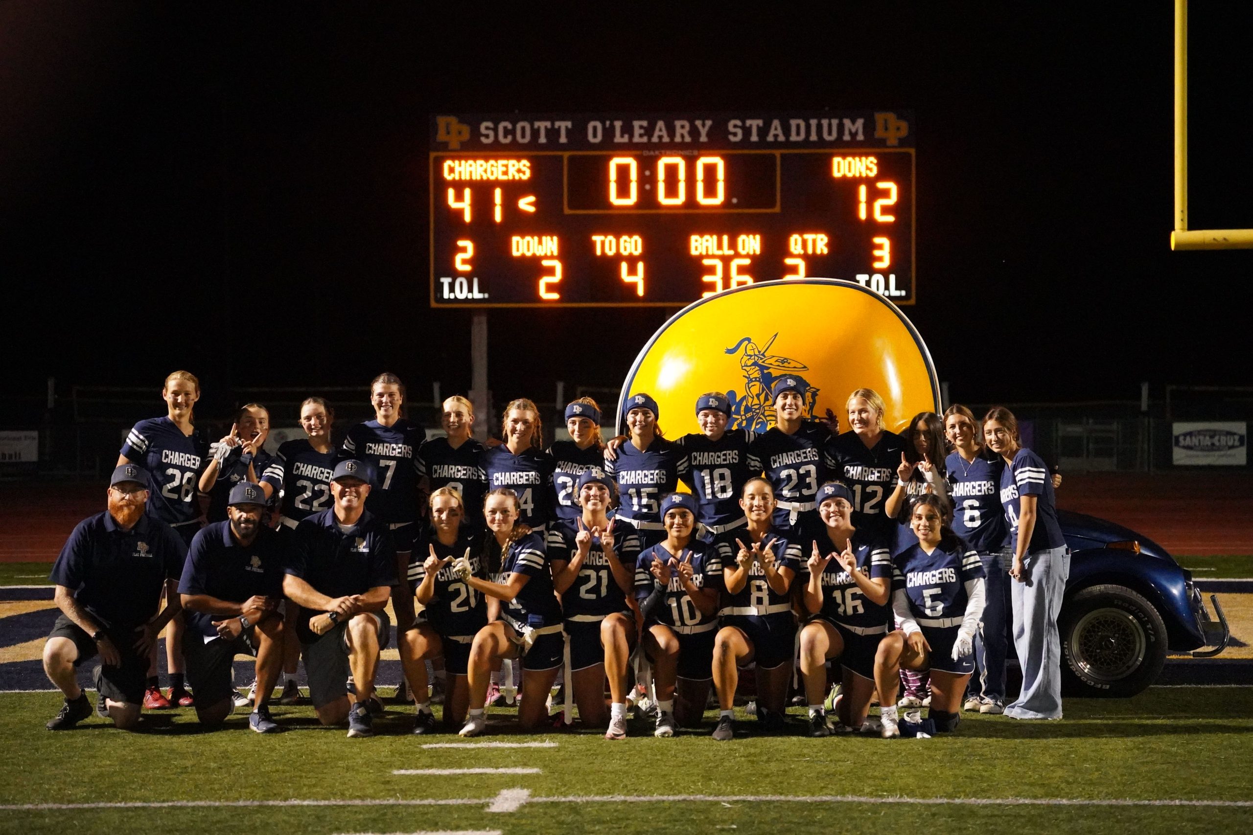 The team poses in front of the scoreboard after their game against the Santa Barbara Dons.