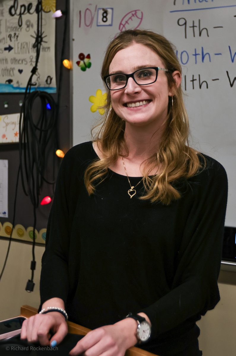 Ms. Derickson is standing at her desk in her DPEA classroom.