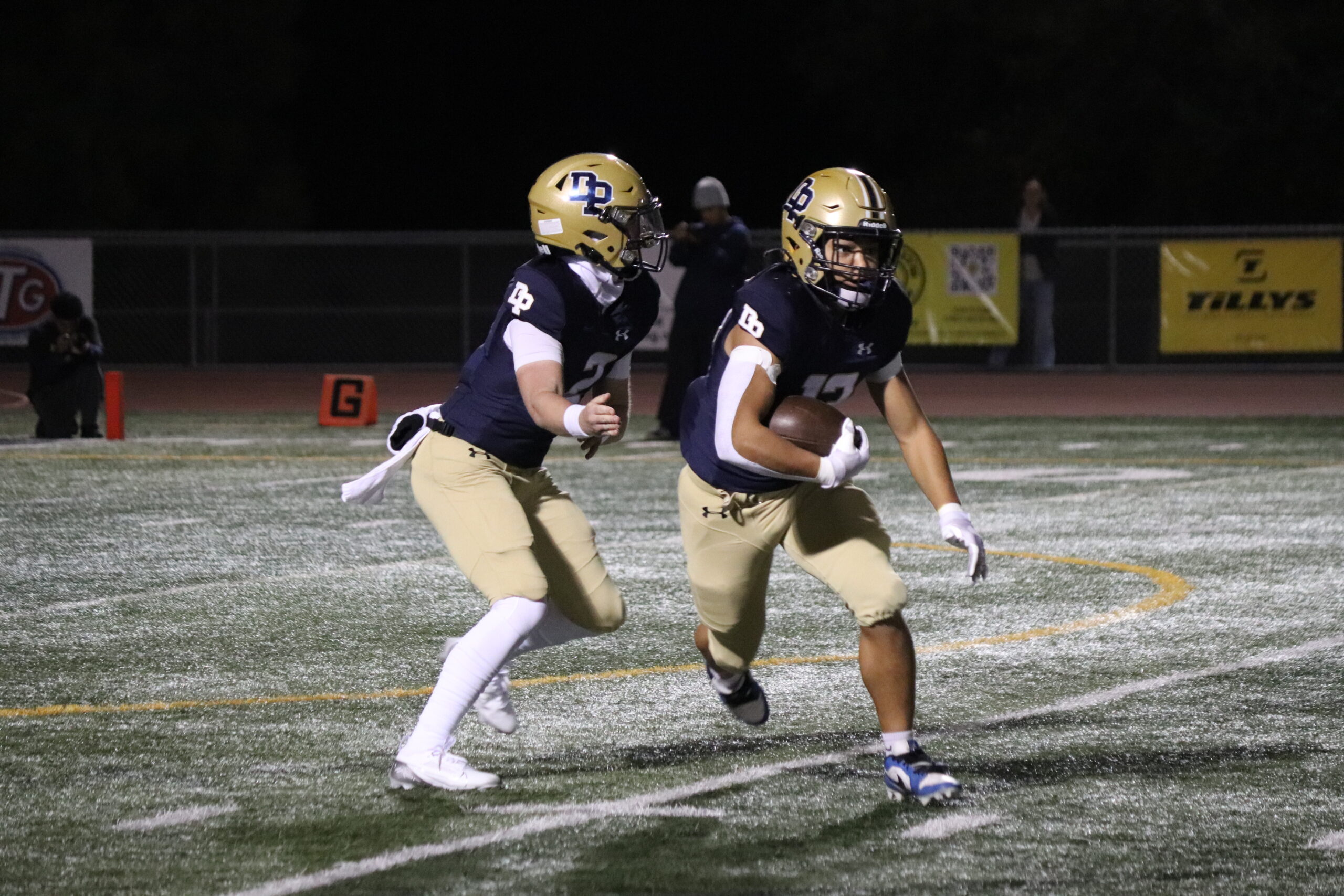 Quarterback Simon Alexander (12) handing off the ball to the running back, Kaleb Williams (12)