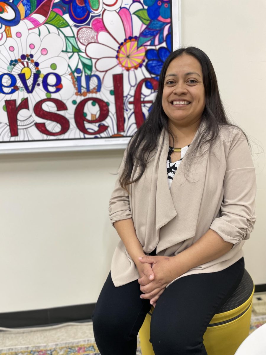 Wellness Coordinator Angela Montañez sits in front of a collaborative poster in the Wellness Center.