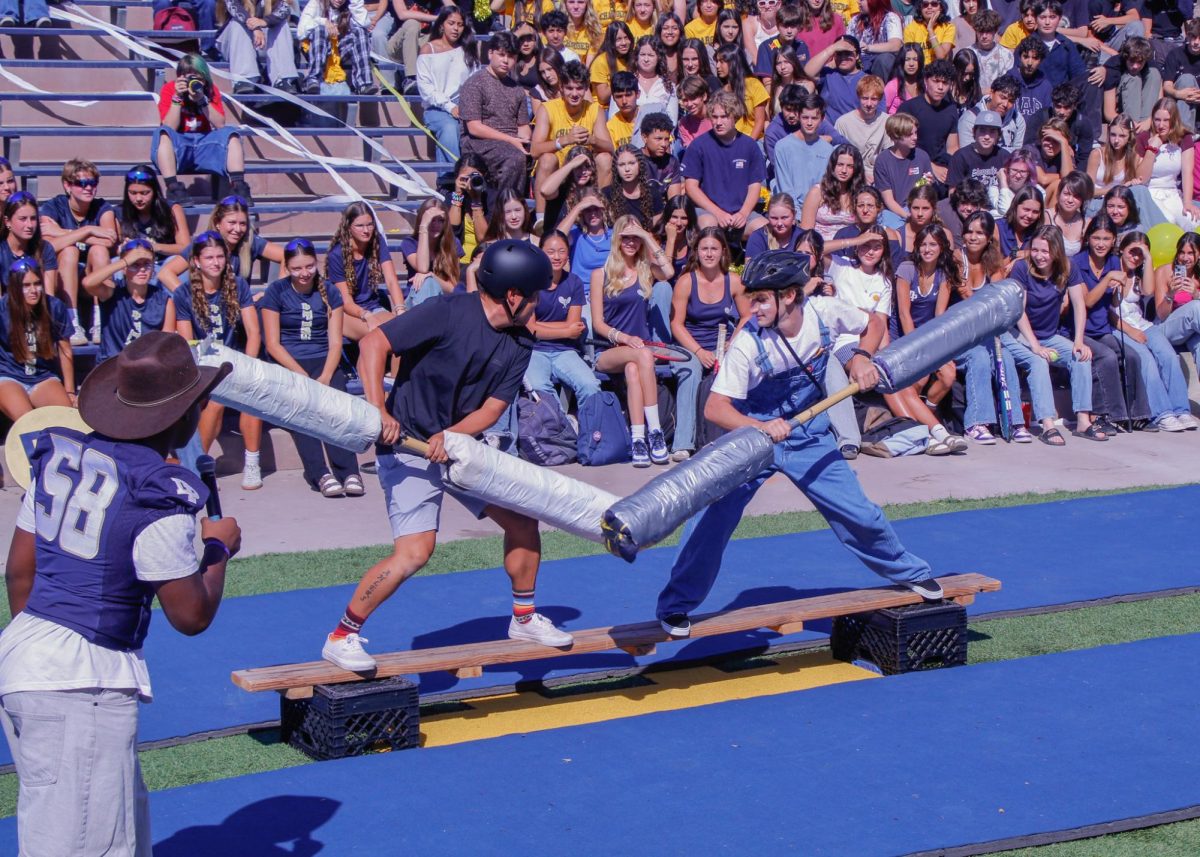Tarkan Ezal (12) and AP Psychology teacher Kevin Ahlers joust on a wooden plank, with their weapons forming a V-shape.