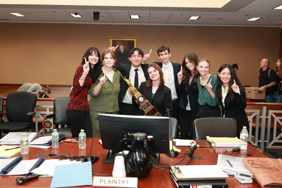 Riley Minne (12) holds first place trophy, surrounded by the DPHS Mock Trial team 