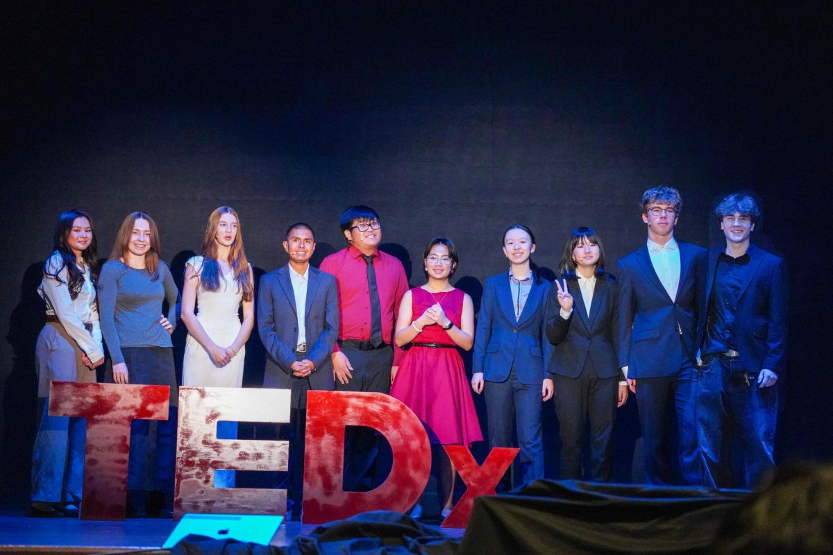 Student organizers and speakers pose by the TEDx sign before the start of the event.